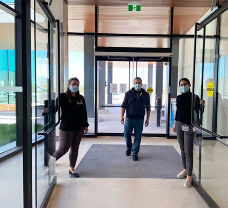Three people opening the doors to the main entrance